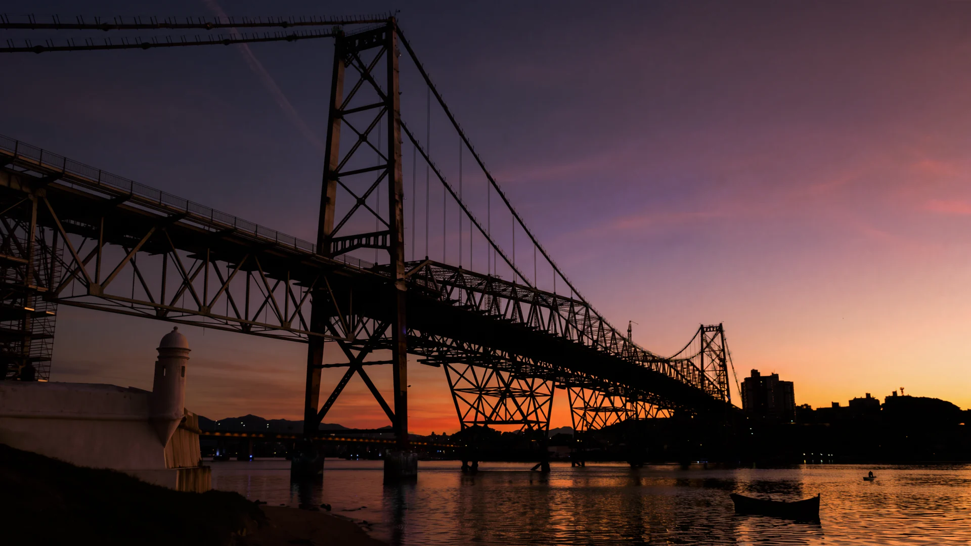 A Ponte Hercílio Luz no crepúsculo, vista do Forte Santana, com as lâmpadas dos cabos acesas