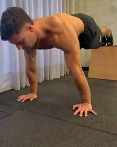 O Luca na flexão declinada, com os pés apoiados num caixote e as mãos no chão.